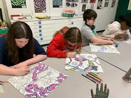 Students drawing with pencils at classroom tables